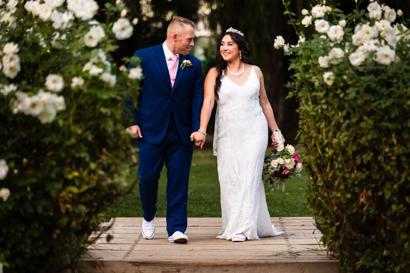 Bride and groom holding hands among the flowers and nature at their outdoor wedding at Galway Downs in Temecula.