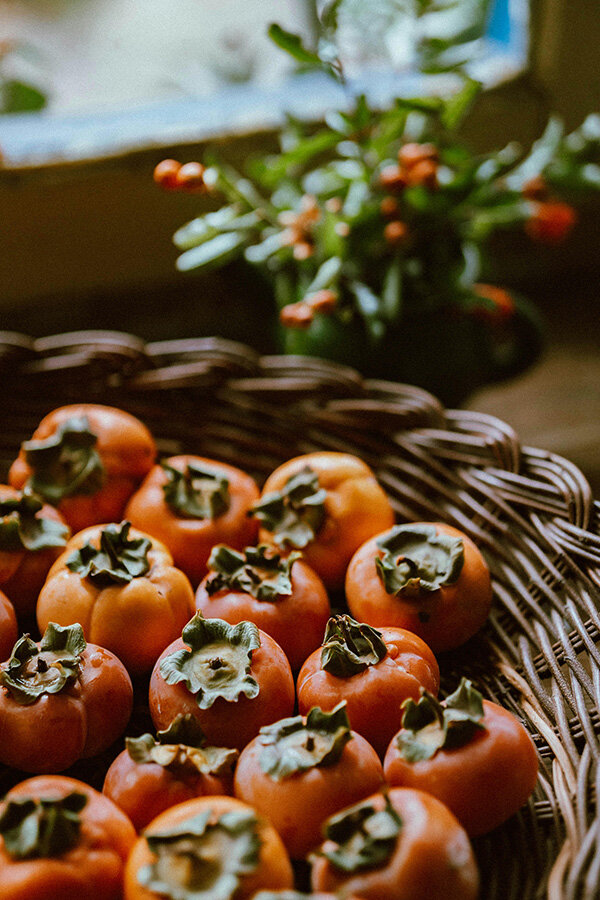 A woven basket filled with bright orange peppers peeking out from the sides.