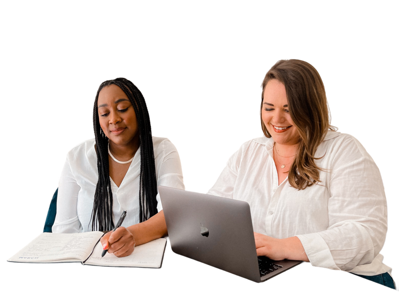 Woman writing in notebook next to a woman working on a laptop
