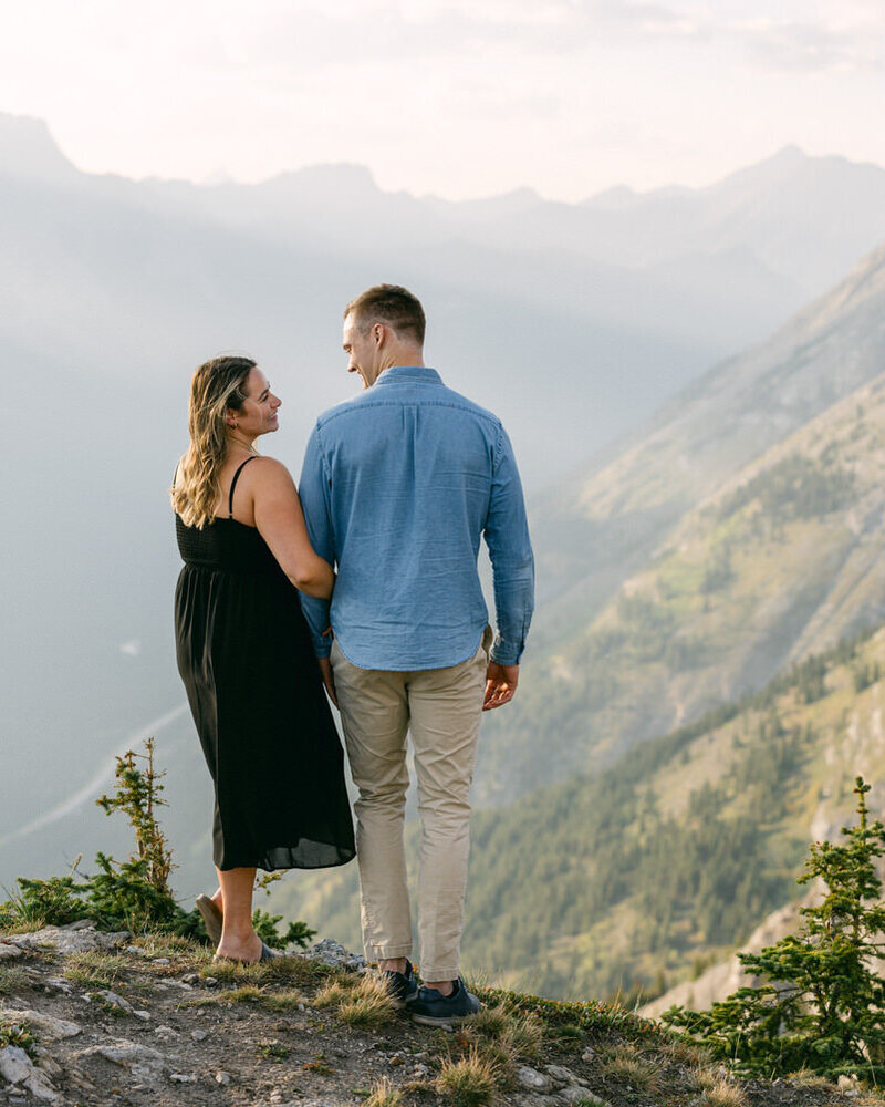 Captured at Lake Louise, the bride smiles back at her groom with the Chateau Lake Louise behind and the stunning Victoria Glacier in the distance.