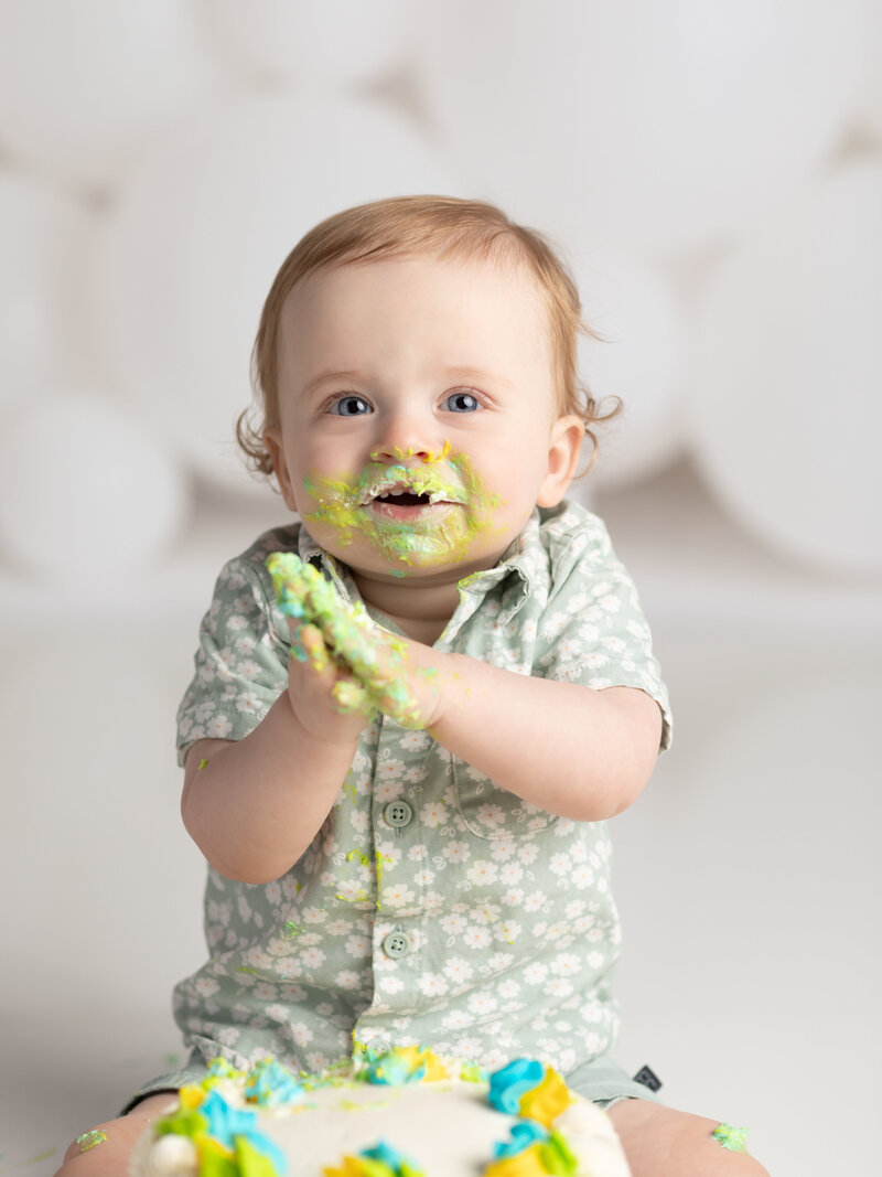 one year old boy eating cake for first birthday cake smash