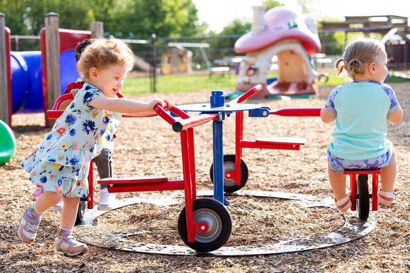 happy toddlers playing outside on the merry go round