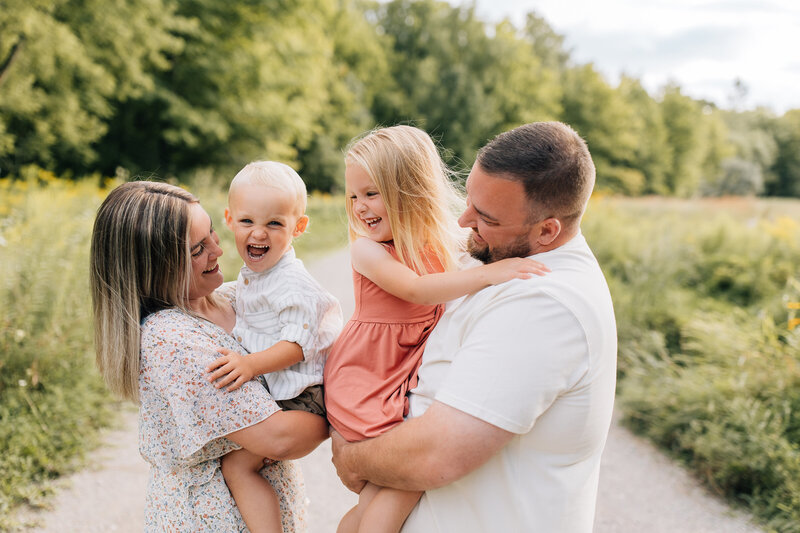 The Sage family during an outdoor photoshoot, smiling and laughing together. 