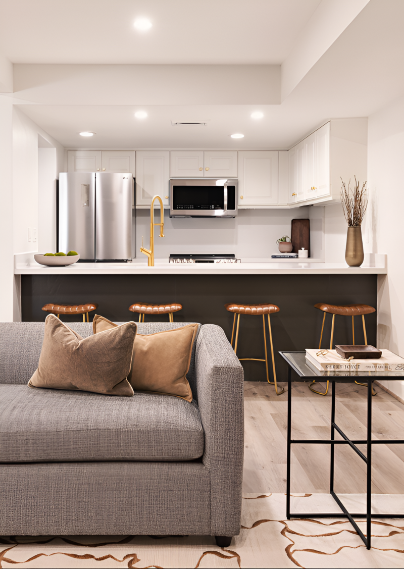 Close up shot of a mountain modern kitchen and view of the living room with a cozy grey couch, white cabinetry and moody accents by Sister Studio.