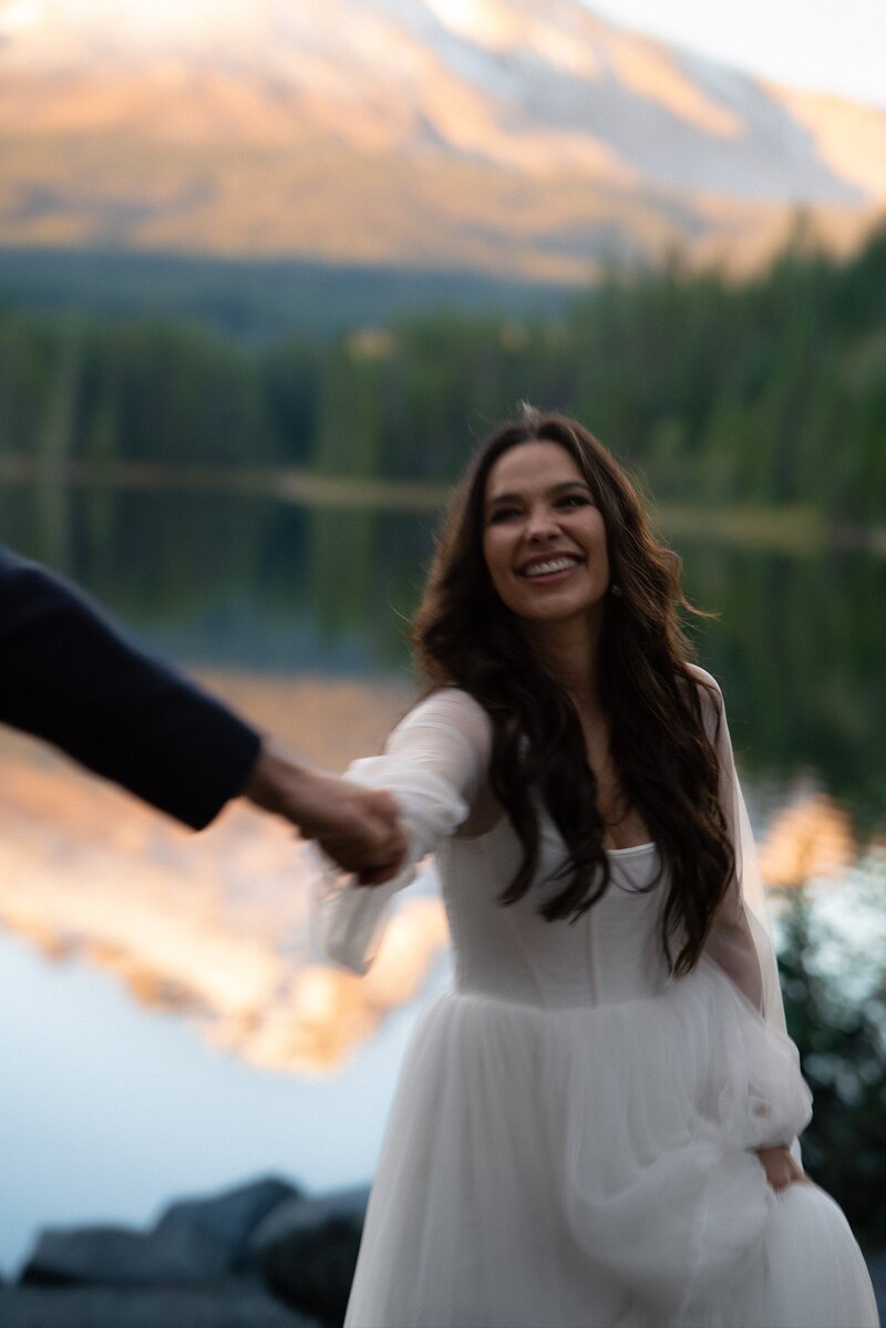 Bride holding Grooms hand laughing on their elopement
