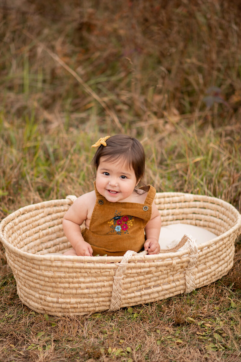 one year old girl in moses basket