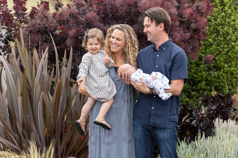 Two parents each smiling and holding a child