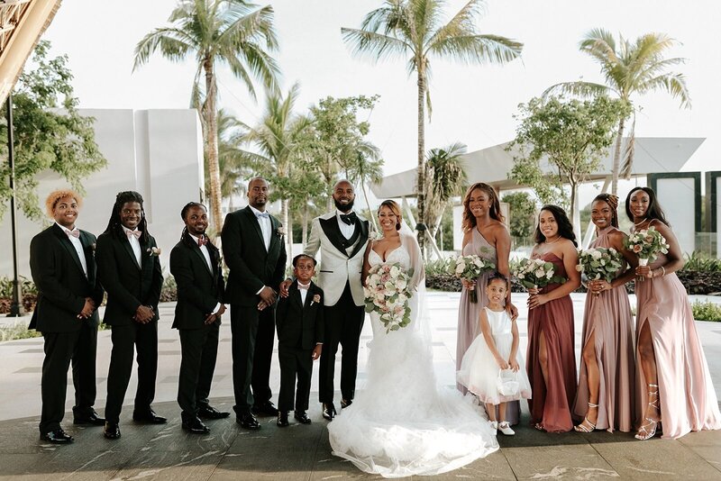 Wedding party poses outside in front of palm trees