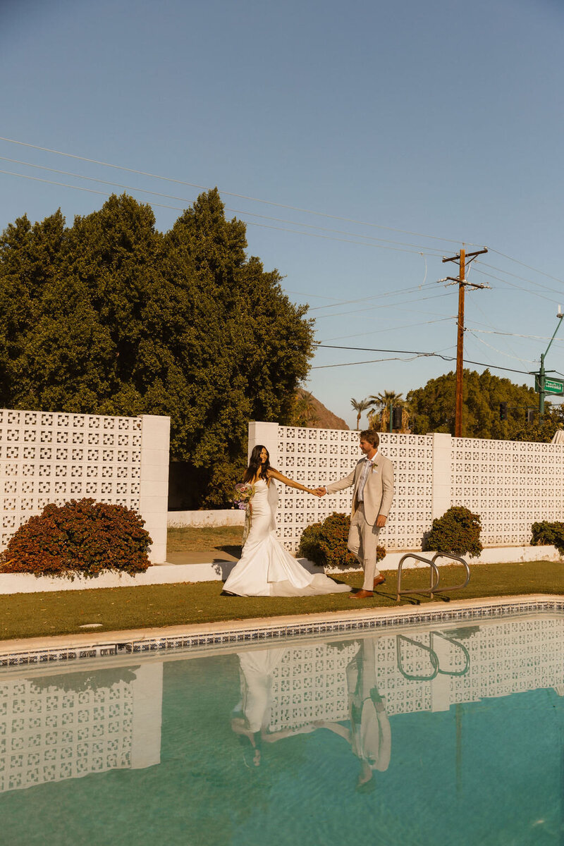 newly weds walk by pool after wedding ceremony in phoenix arizona