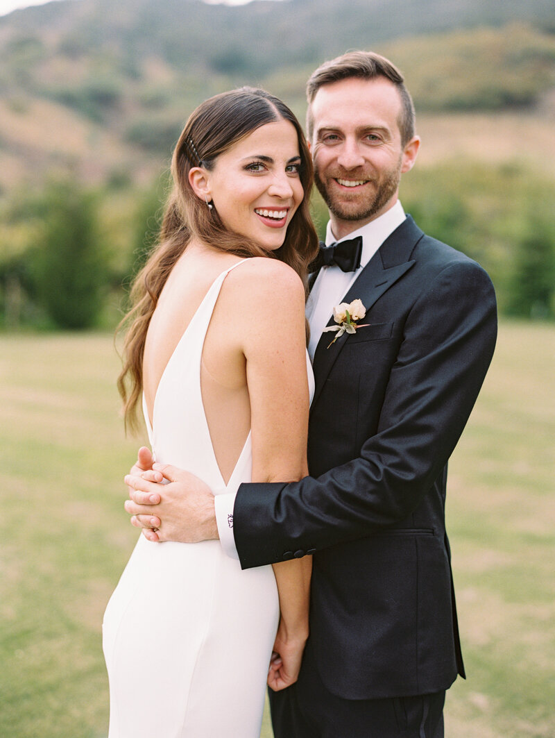 Groom embraces his smiling bride on their wedding day at Klentner Ranch in Montecito