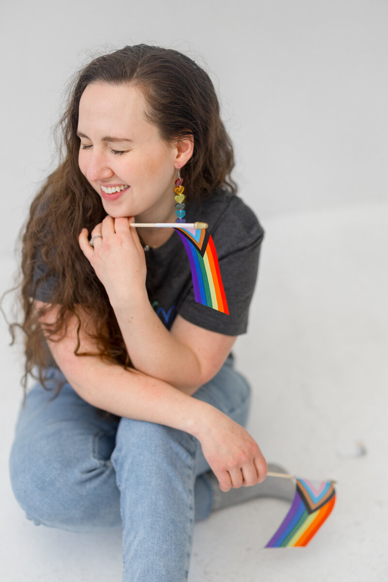 business coach for women - LGBTQIA friendly - holding a rainbow flag and laughing