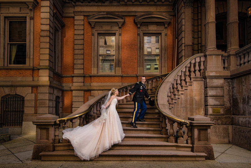 Elegant wedding moment as a groom in uniform guides his bride up the Union League steps in Philadelphia.