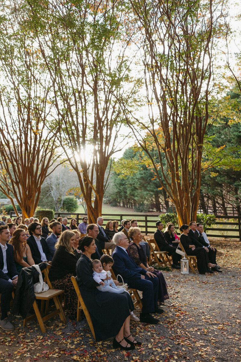Guests watching vows being exchanged during a fall ceremony in the mountains of North Carolina at Hawksdene venue, by Andrea-Marie Photography