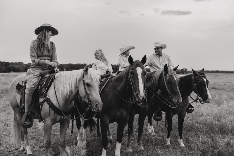 Outdoor family photo session in Wyoming, with a family posing with their horses in a scenic ranch setting, showcasing a relaxed and rustic vibe.