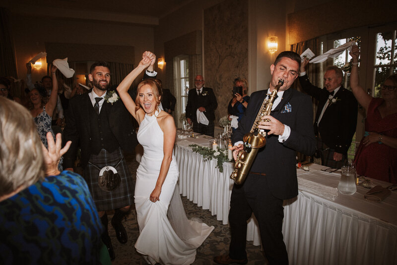 bride and bridal party in silk gowns sitting in bath drinking champagne fun alternative wedding photographer scotland
