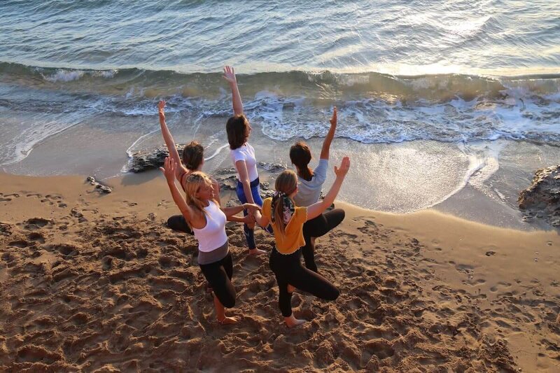 Group of graduates balancing in tree pose by the ocean.