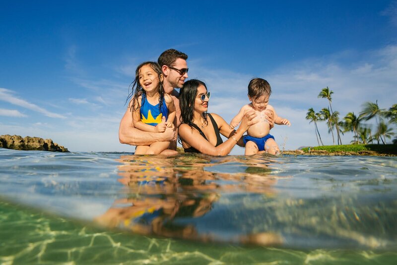 A family plays with their two children in the water.