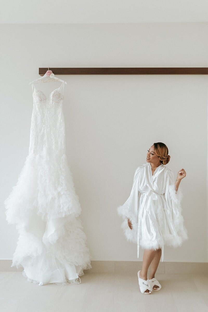 Garza Blanca bride looks at her hanging wedding dress in silk robe