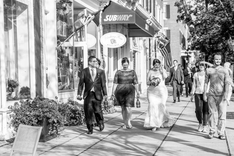 Black and white photo of a bridal party and family walking to the ceremony