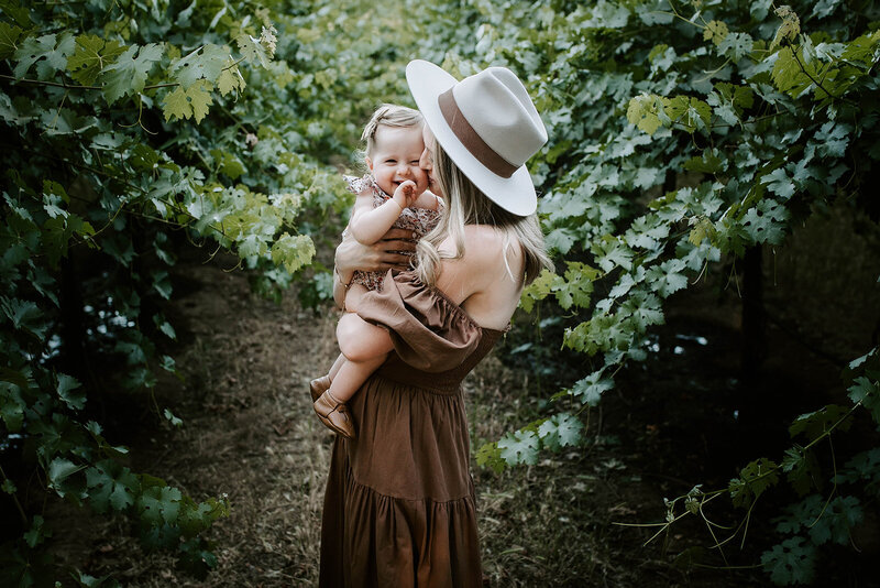 mom holding baby girl in vineyard