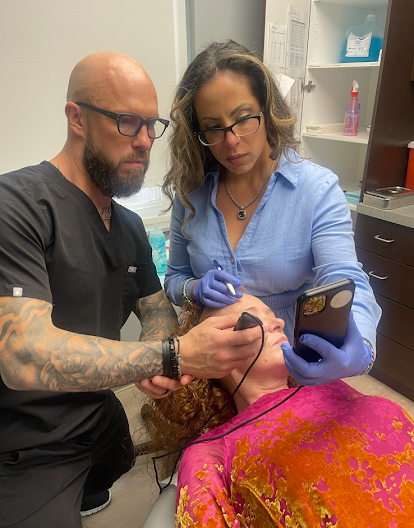 Tara and Chris Koch, co-owners of Refined Medical NY, assisting with a facial treatment using advanced tools at the East Setauket Long Island med spa, specializing in aesthetics, injectables, and dermatology services.
