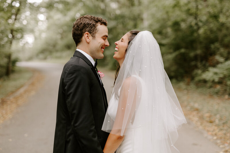 Brunette bride and groom laughing together while facing each other in St. Louis