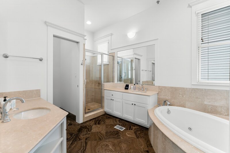 Elegant soaking tub and glass walk-in shower in luxury Panama City Beach vacation rental.