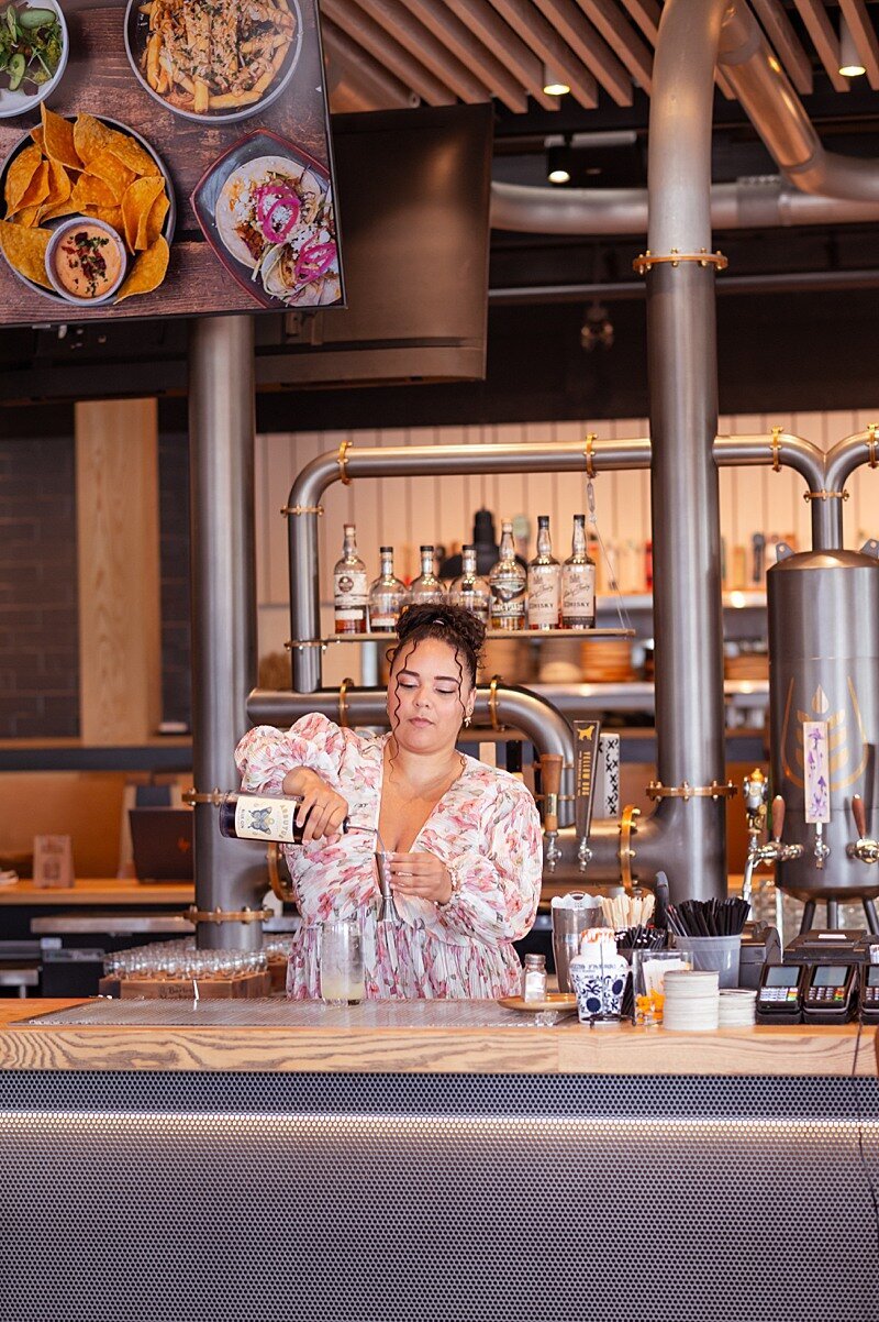 Female bartender pouring alcohol into a shot glass behind a bar