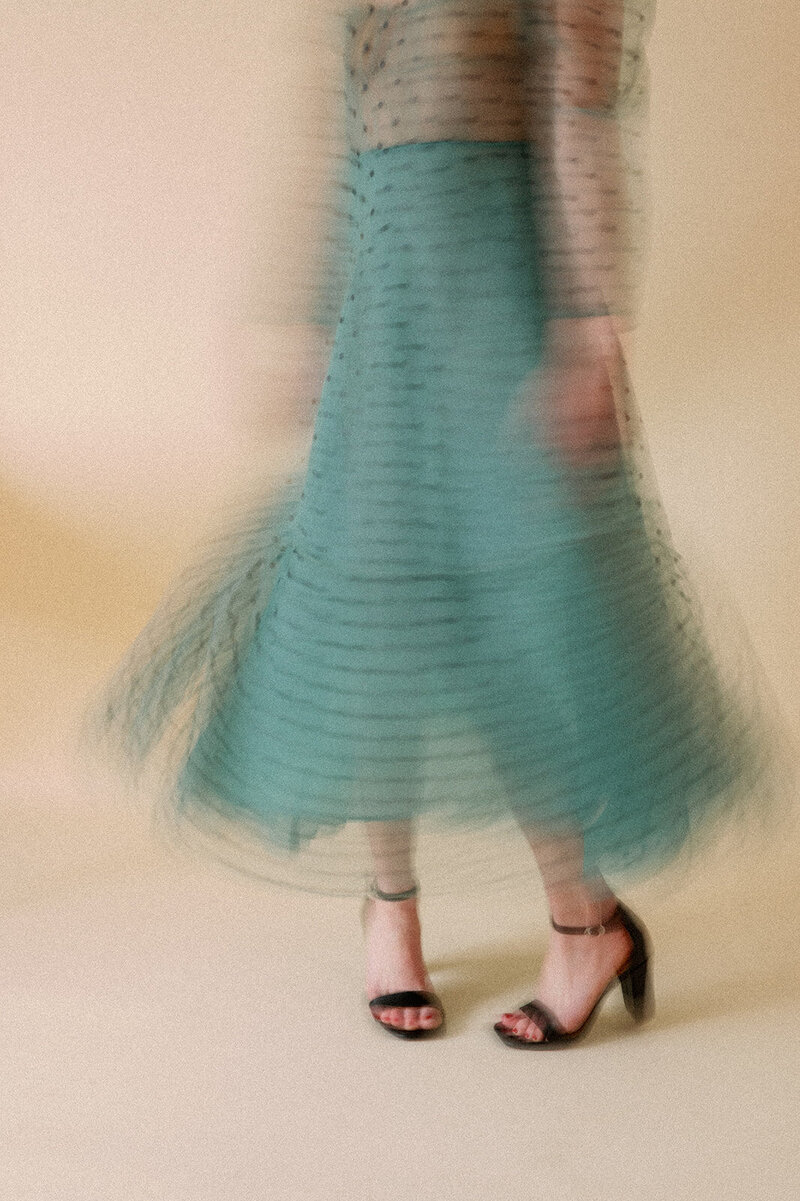 Blurred photo of a woman twirling her teal and black polka dot dress