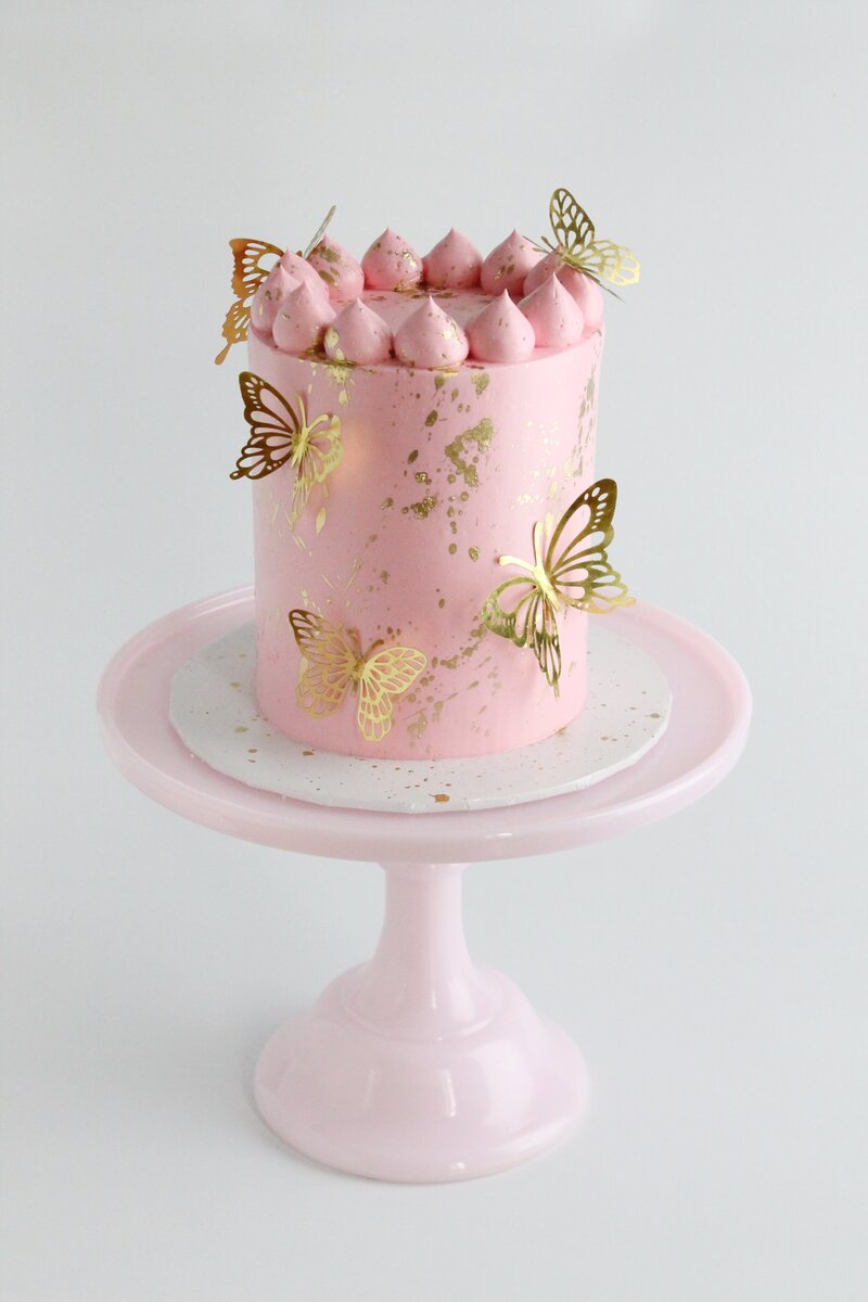 Pink cake with frosting and gold butterflies