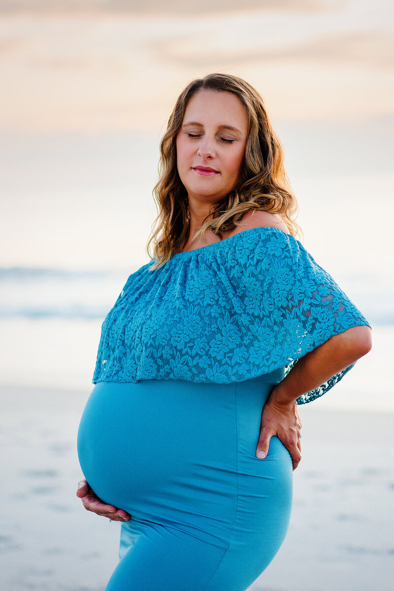 Pregnant mom in form fitting blue dress at Atlantic Beach, FL.