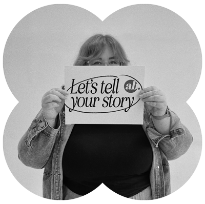 Web designer, annie b. holding a sign that says, "Let's tell your story"
