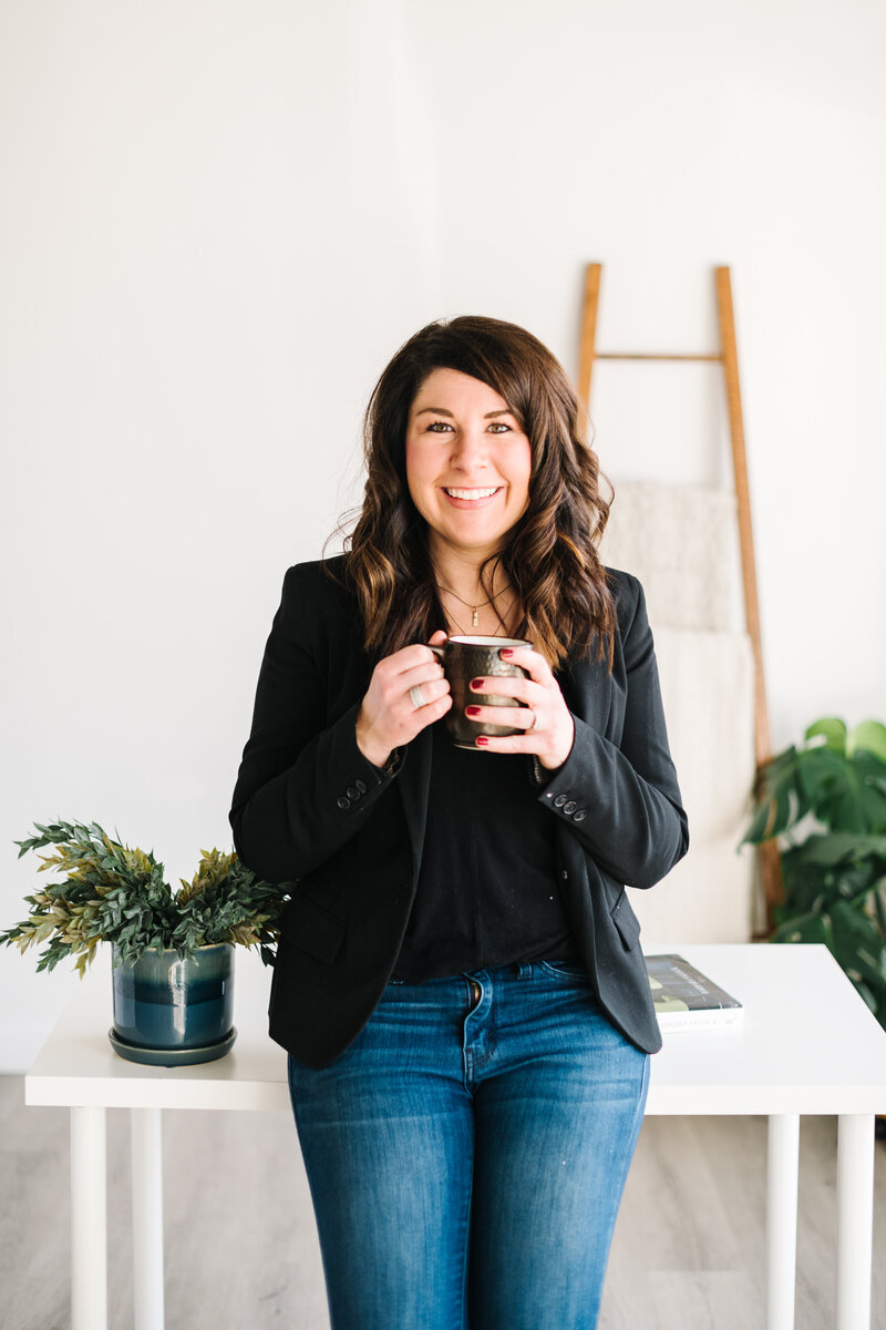 An interior designer holding a coffee cup in her bright and airy office