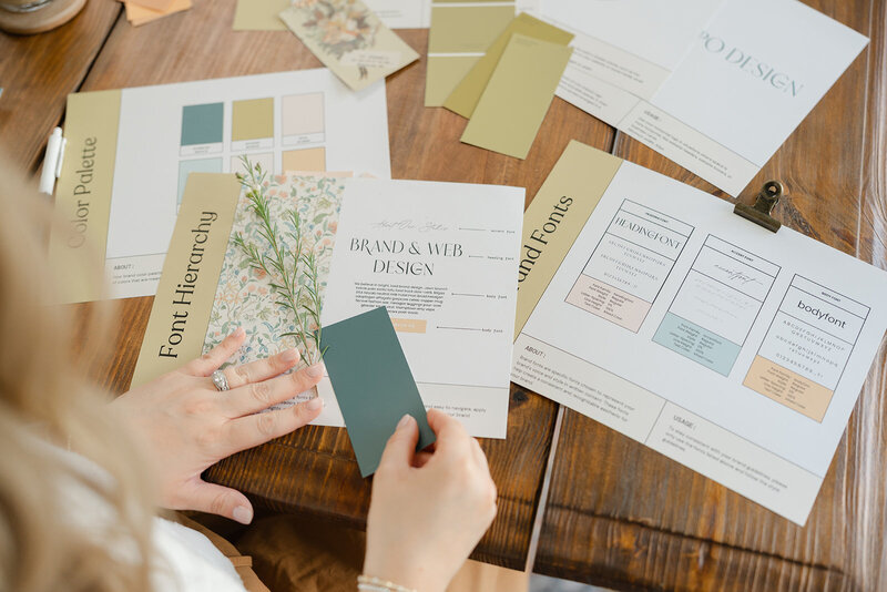 Hands holding a color swatch over top of printed brand guidelines book
