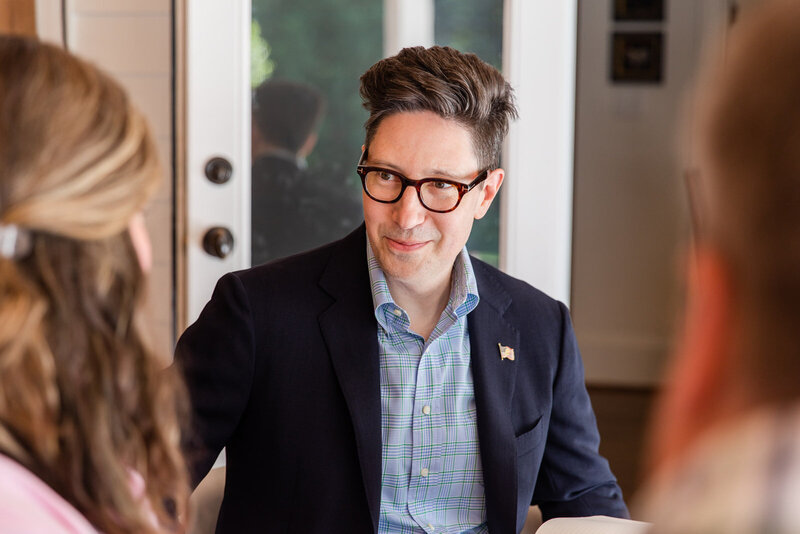 man in blue shirt and navy blue jacket talking to clients during a meeting by laure photography