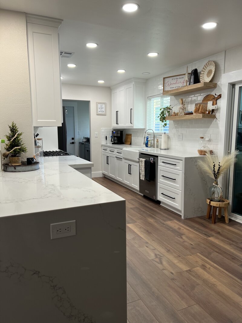A new kitchen remodel with white countertops, white cabinets, and black hardware