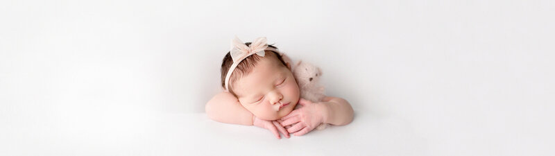 Baby girl with pink headband and pink stuffed bear