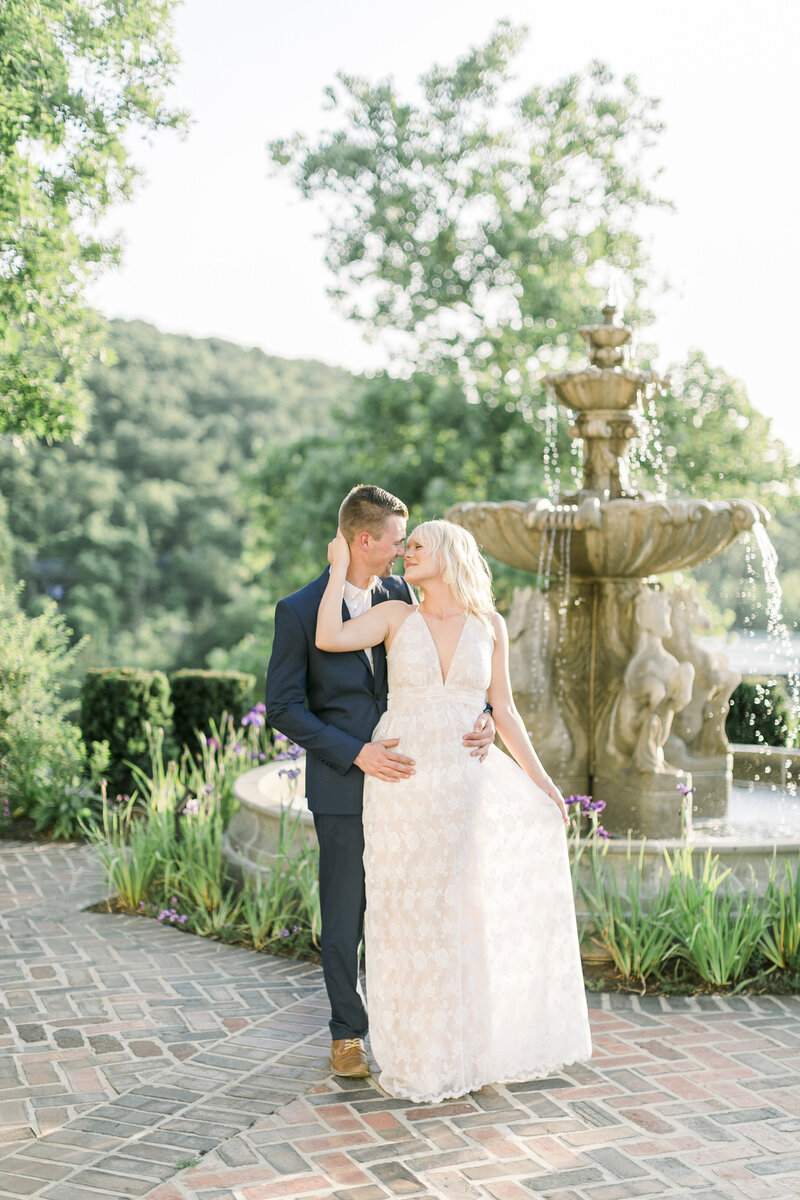 bride-and-groom-at-big-cedar-lodge-worman-house-fountain-with-purple-irises-groom-with-navy-blue-tux-by-branson-wedding-photographer-kathryn-faye-photography