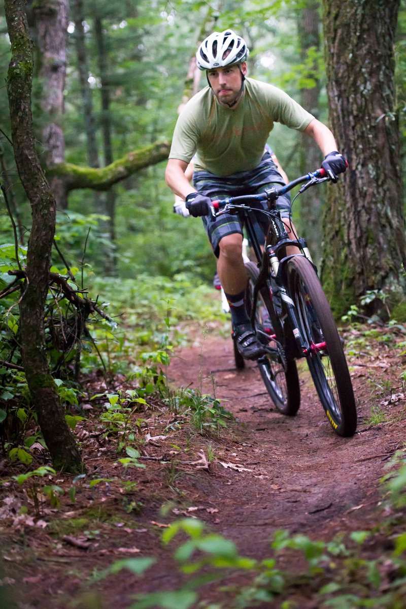 a man and woman mountain biking during a couple's adventure session in a dense forest in the southeast