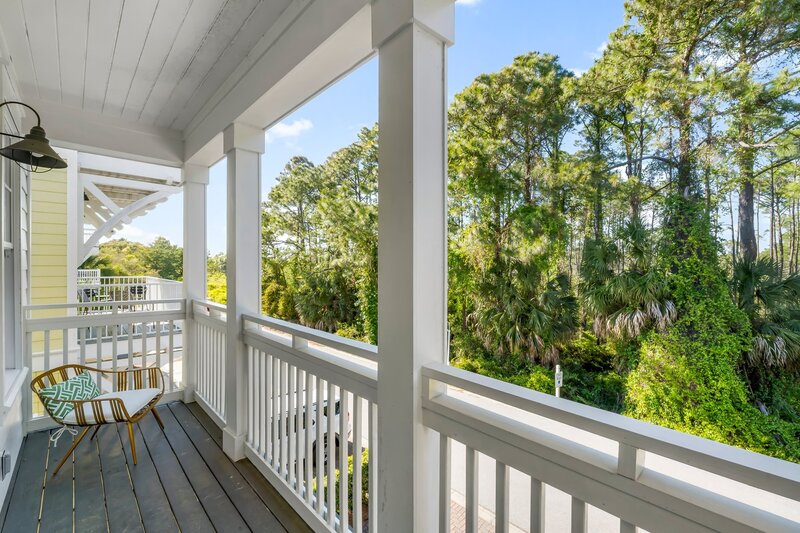 Intimate upper-level balcony with a single chair and view of the forest-lined street