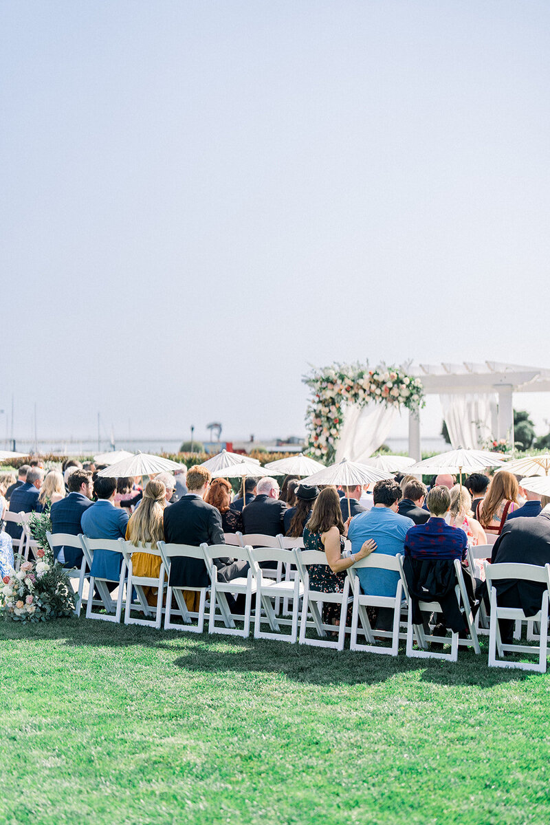A stunning California wedding ceremony captured with the couple sharing their first kiss under a floral-draped pergola. Surrounded by lush greenery and an ocean breeze, this moment epitomizes the elegance and beauty of a romantic, outdoor California wedding. Perfect for couples seeking a dreamy, coastal backdrop.
