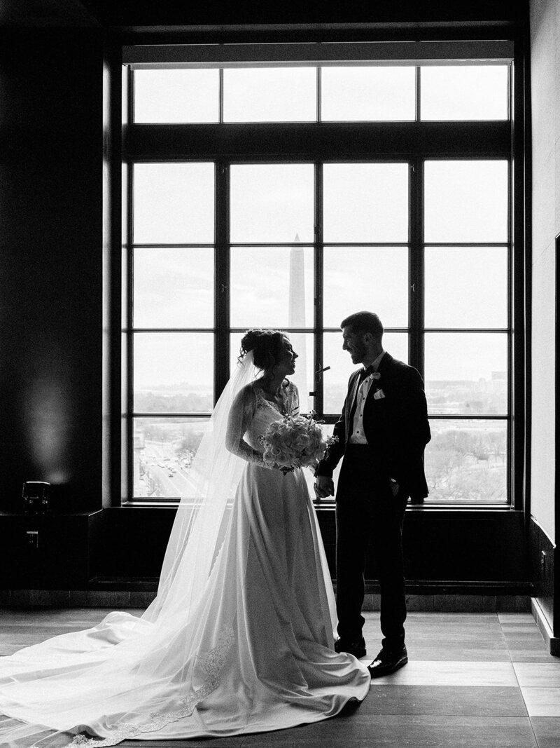 Wedding photo in black and white of couple  near window in a hotel.