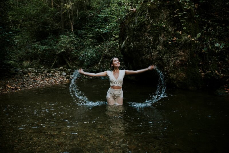 A woman standing in the forest river, playing with water
