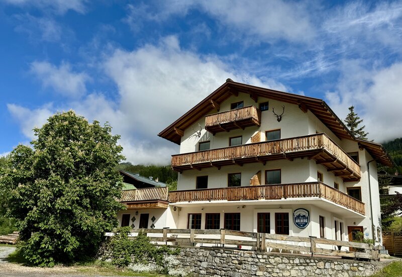 Traditioneel Oostenrijks chalet Haus Arlberg met besneeuwde bergtoppen in Sankt Anton am Arlberg.
