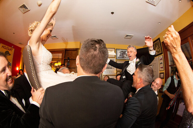 Bride and groom carried by their guests for celebration