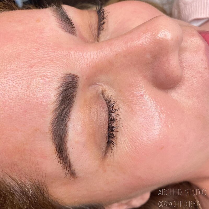 Female enhanced eyebrows that look naturally fluffy, through nicroblading services at ARCHED Coastal in Gulf Shores, Alabama.