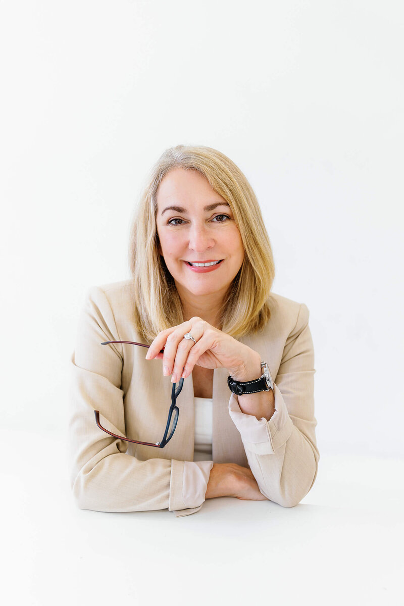 Melissa Greenewll, leadership coach for c-suite executives, headshot, holding her glasses