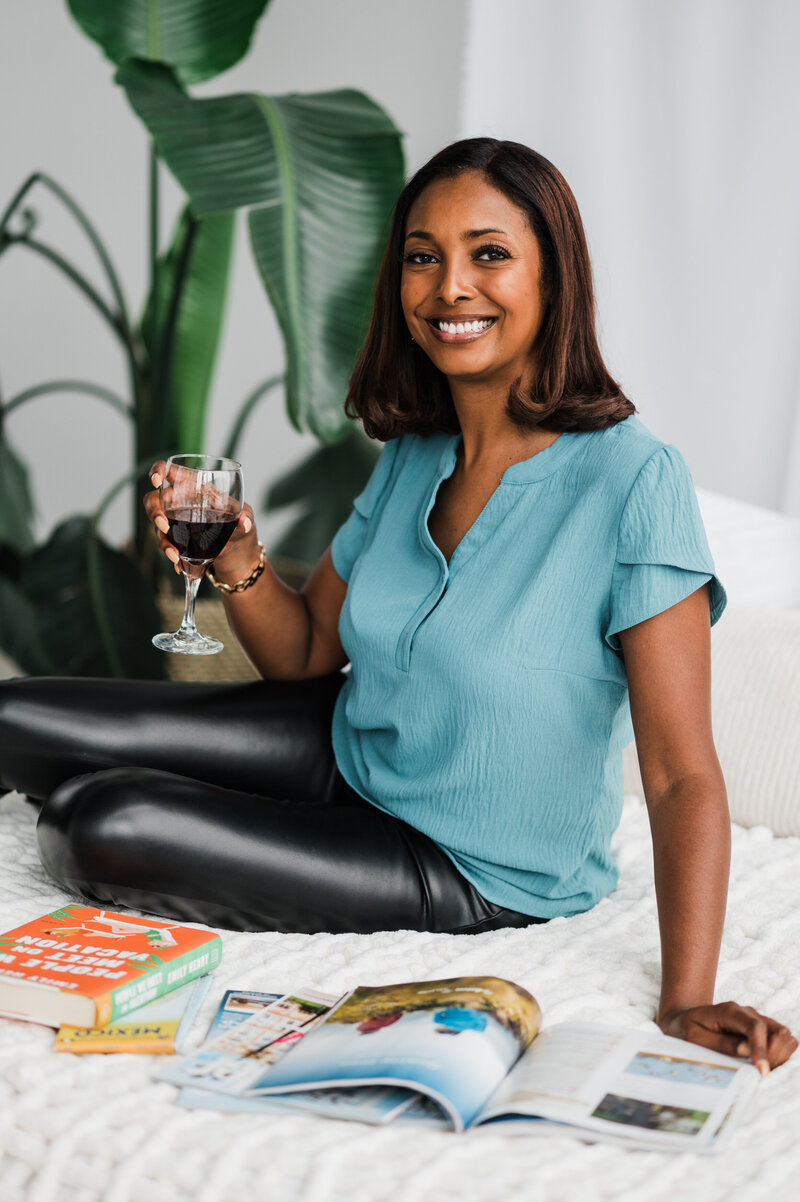 A woman relaxes on a couch, enjoying a glass of wine, embodying the elegance of a destination wedding planner.
