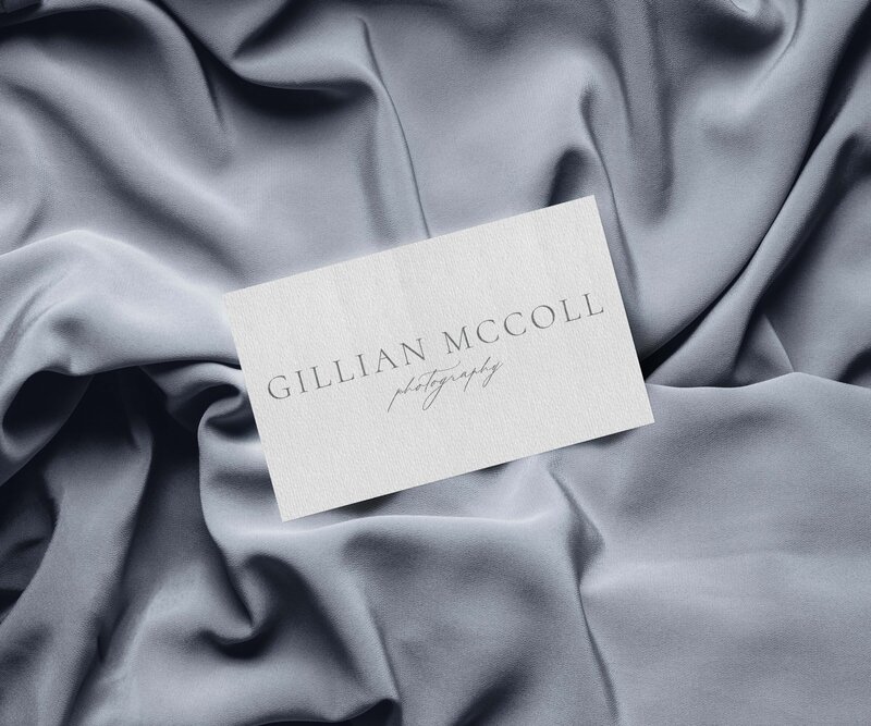 A business card with the name "Gillian McColl Photography" lies on a backdrop of smooth, grey fabric, perfectly crafted with website design services for small business.