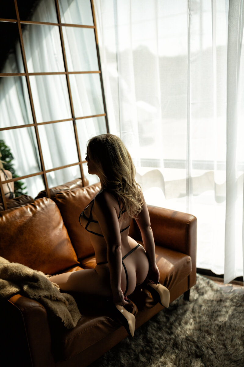 woman sitting on couch in black lingerie